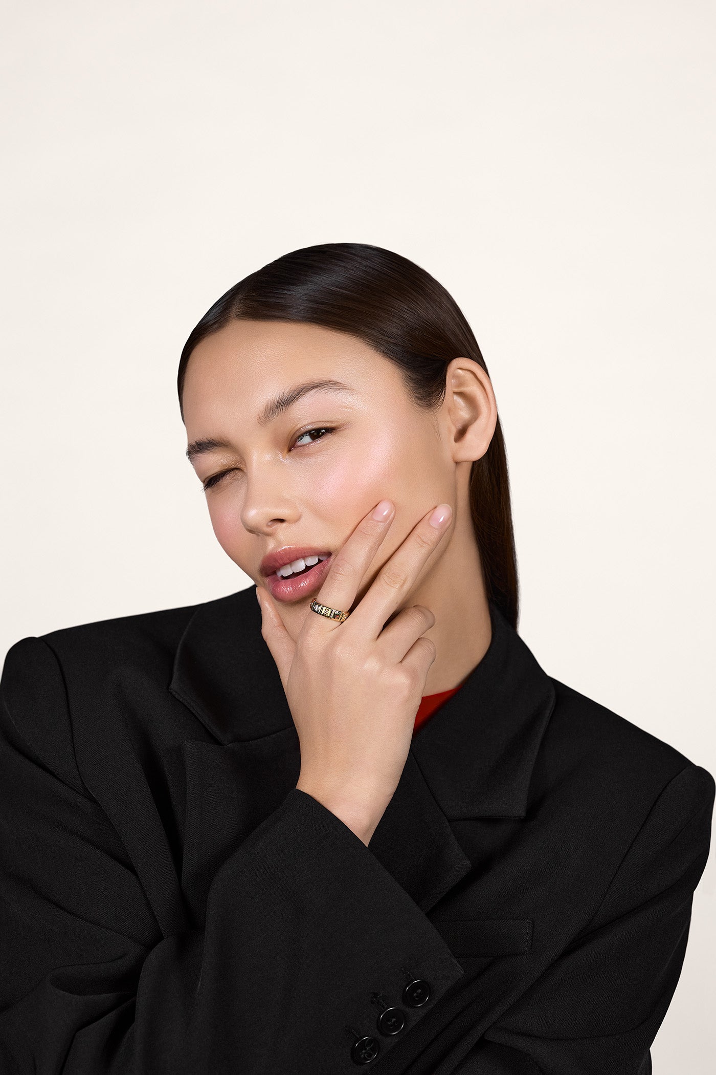 A young woman wearing a black blazer and wearing a gold ring on her index finger.
