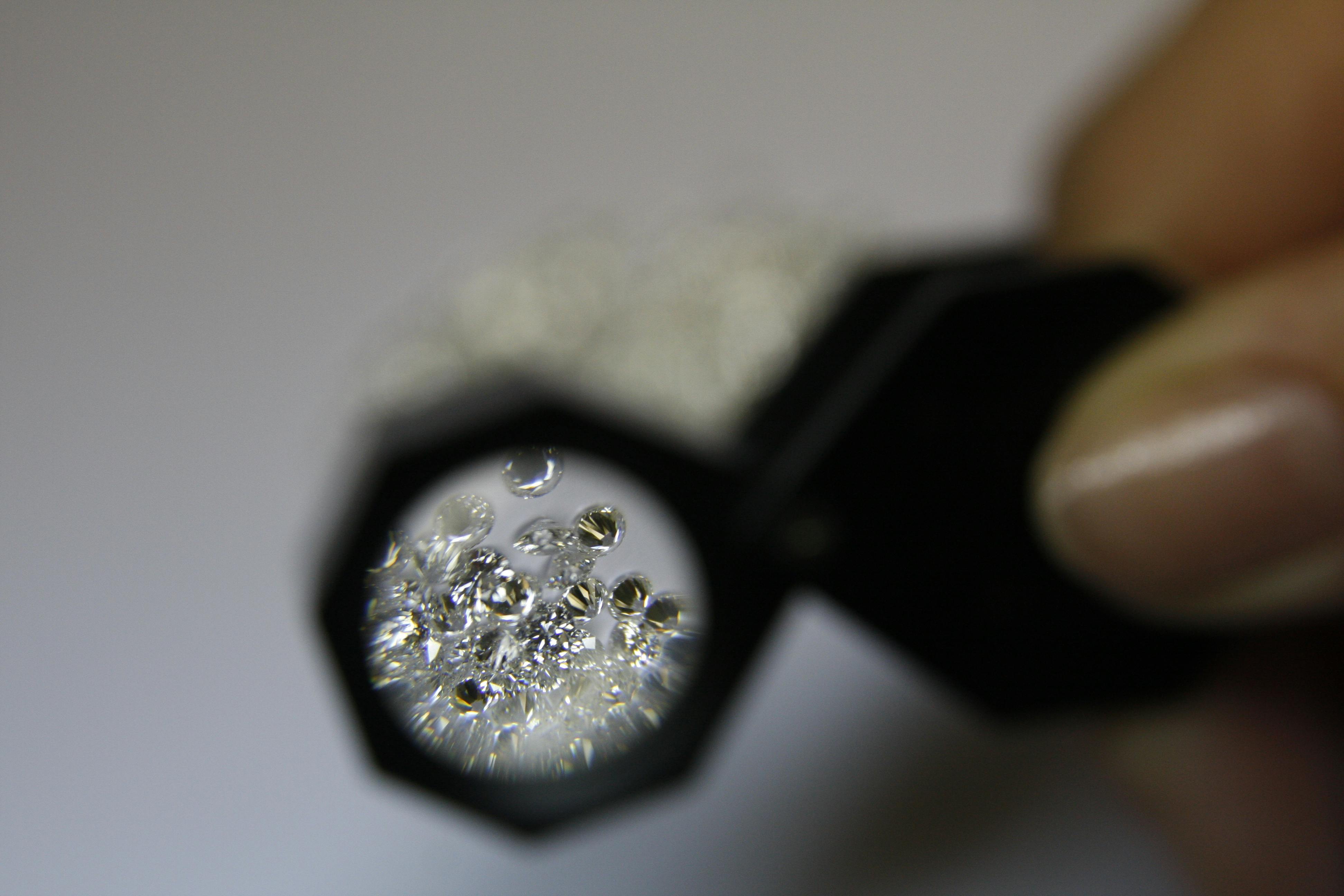 Numerous diamonds examined through a jeweler’s loupe.