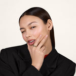 A young woman wearing a black blazer and wearing a gold ring on her index finger.