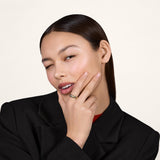 A young woman wearing a black blazer and wearing a gold ring on her index finger.