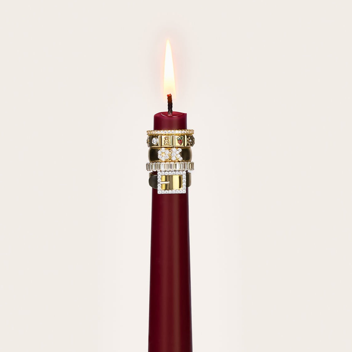 A red burgundy candle with 5 rings stacked on it.