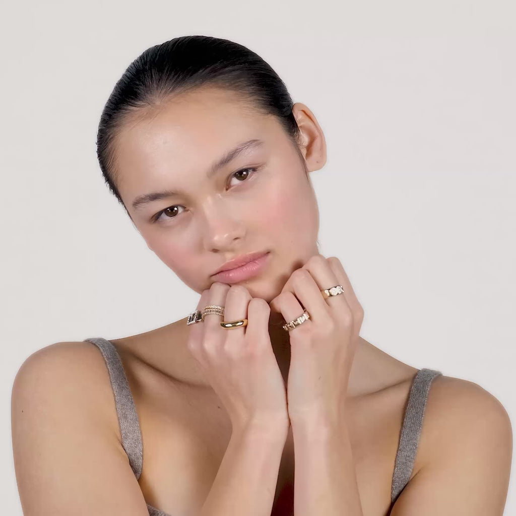 A video of a young woman wearing gold rings on all of her fingers.