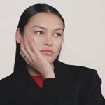 A video of a young woman wearing a black blazer and wearing a gold ring on her index finger.