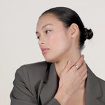 A video of a young woman wearing a bold gold ring that says "OK" on her index finger.